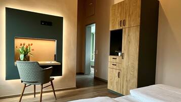 Une chambre d’hôtel moderne équipée d’un bureau, d’une chaise, d’une armoire et de deux lits.