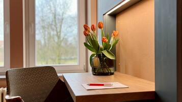 Un bureau en bois sur lequel se trouve un vase de tulipes oranges, un stylo rouge et une feuille de papier.