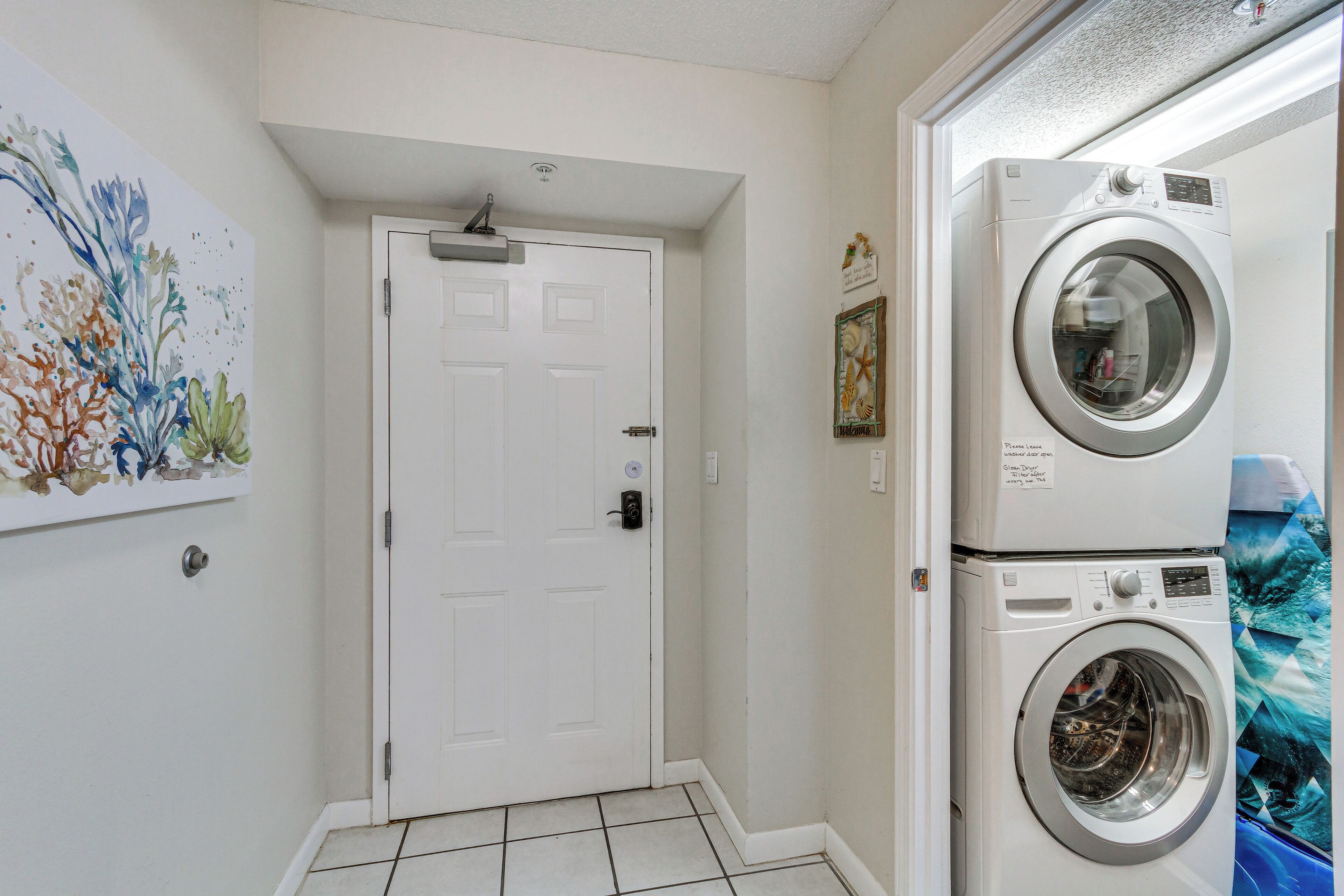Un espace buanderie avec une porte, un lave-linge fixé au mur et un sol carrelé.