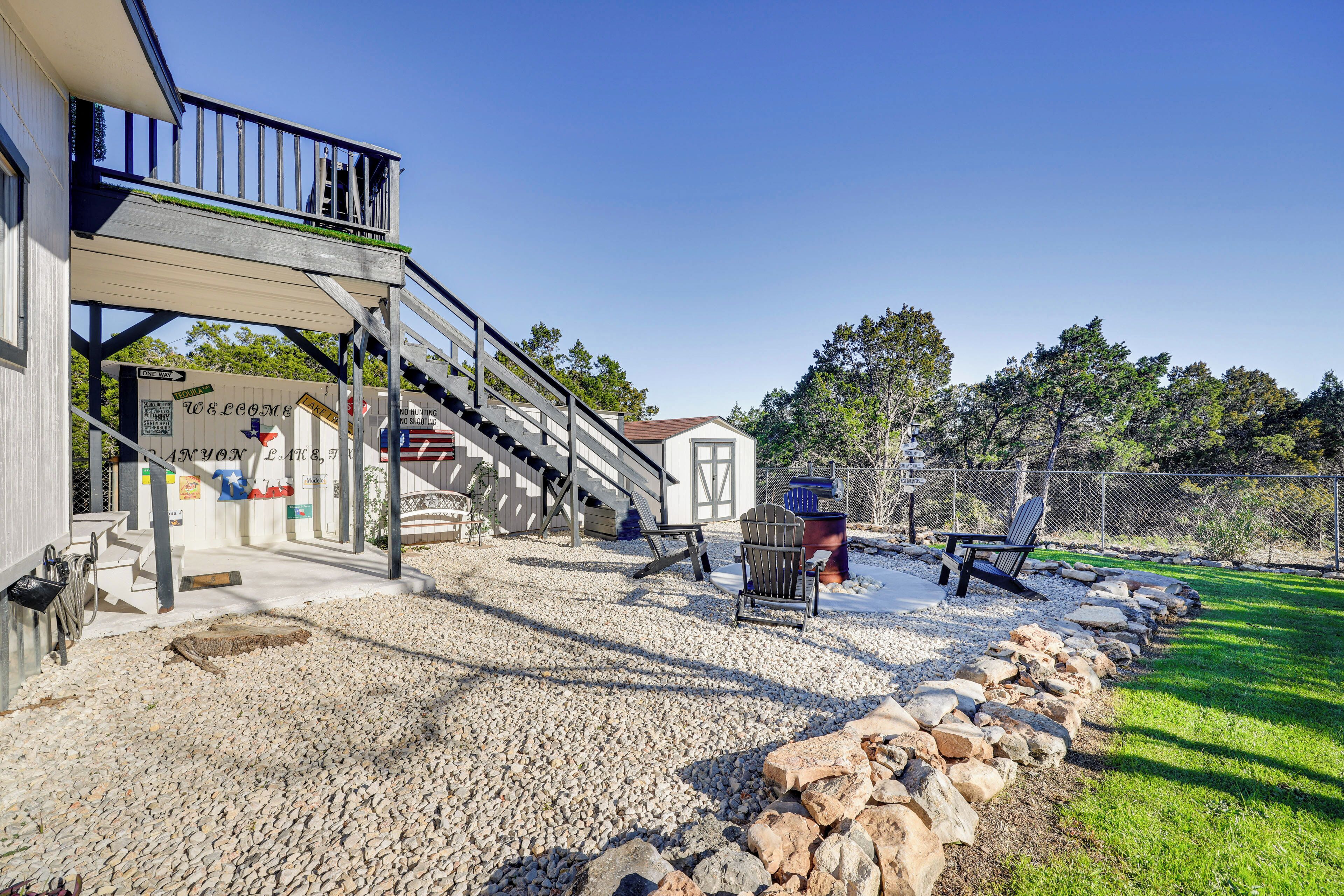 A building with a covered outdoor area, a gravel driveway, and a wooden fence.