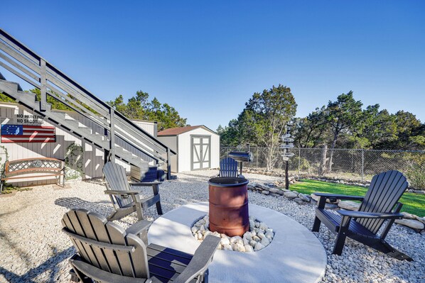 A patio area with Adirondack chairs, a fire pit, and a wooden deck with a 'No Hunting' sign.