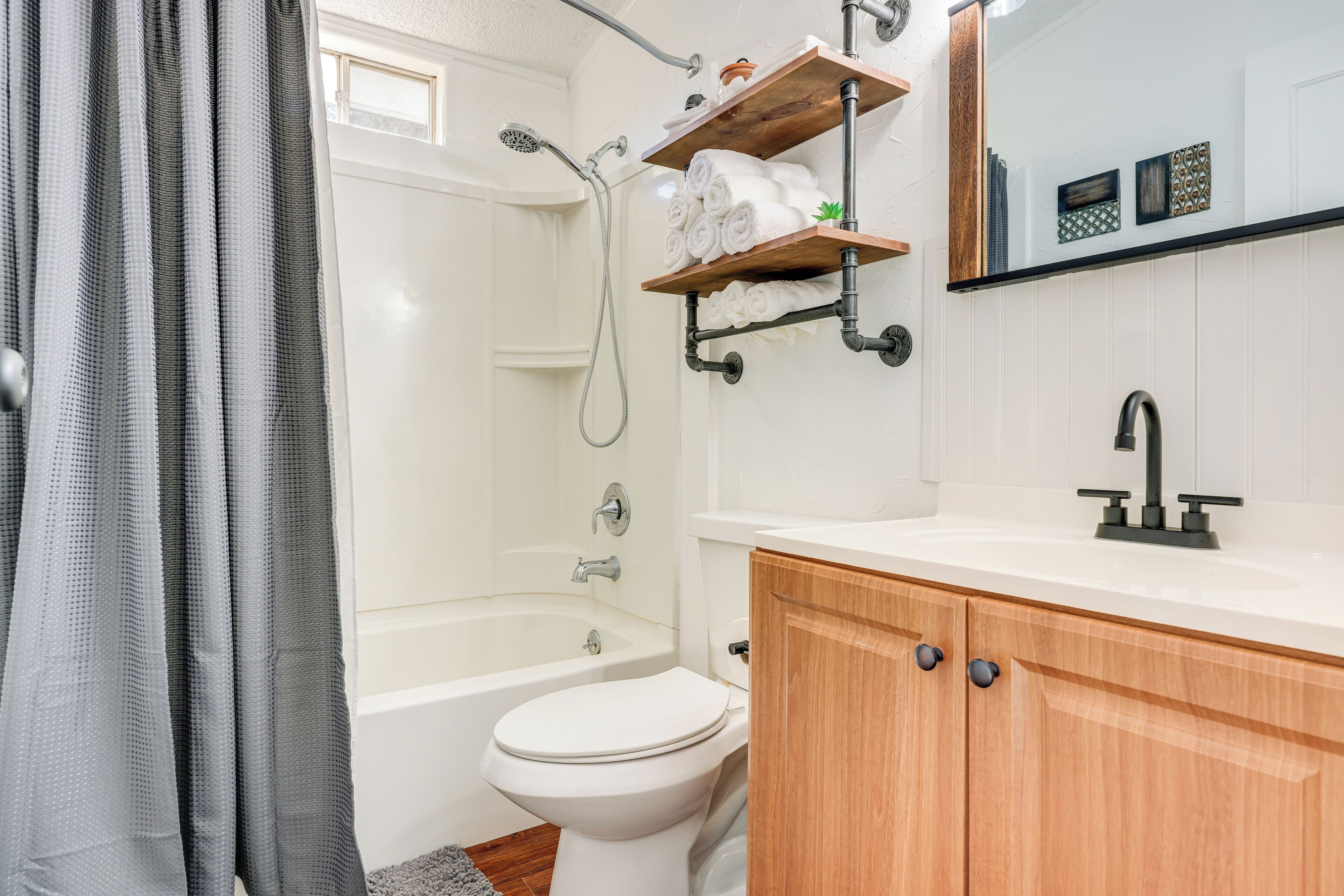 A bathroom with a bathtub, toilet, and a vanity with a mirror.