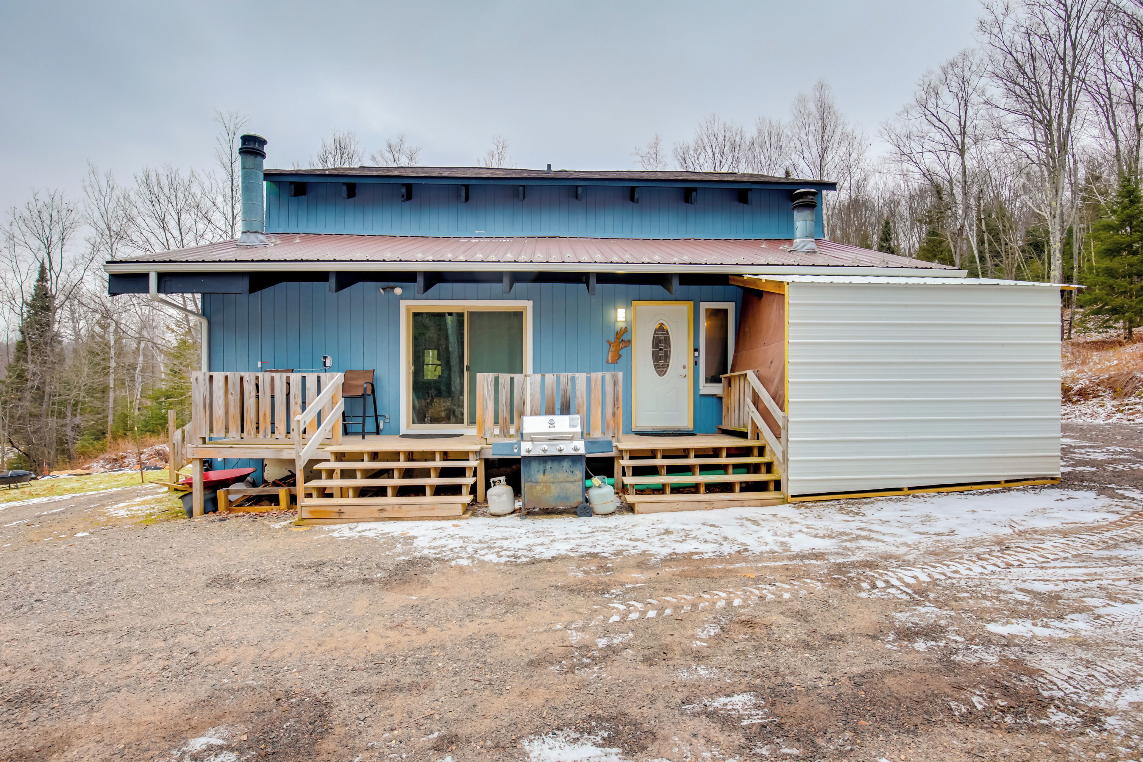 Une cabane rustique dotée d’une terrasse en bois, d’une porte d’entrée et d’une cheminée.