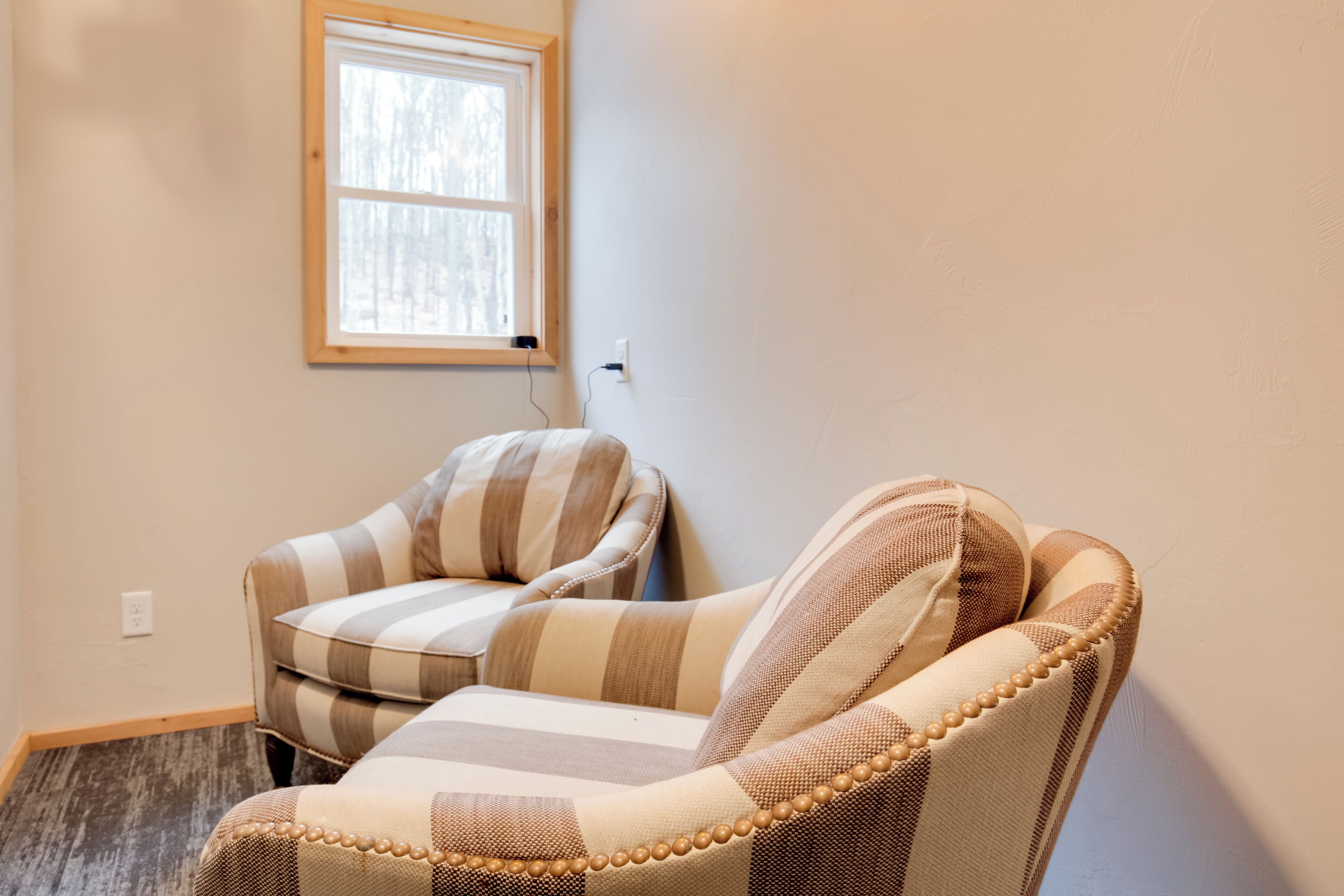 Une pièce d’angle avec un fauteuil à rayures et une petite table.