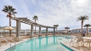 A swimming pool with a pergola, palm trees, and lounge chairs. - PCB Townhome w/ Deck & Pool Access: 3 Mi to Beach! (Panama City Beach)