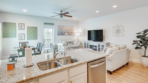 A modern kitchen with granite countertops, a built-in dishwasher, and a dining area with a table and chairs. - PCB Townhome w/ Deck & Pool Access: 3 Mi to Beach! (Panama City Beach)
