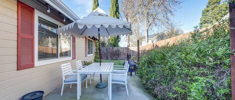 A patio with a table and chairs, an umbrella, and a barbecue grill.