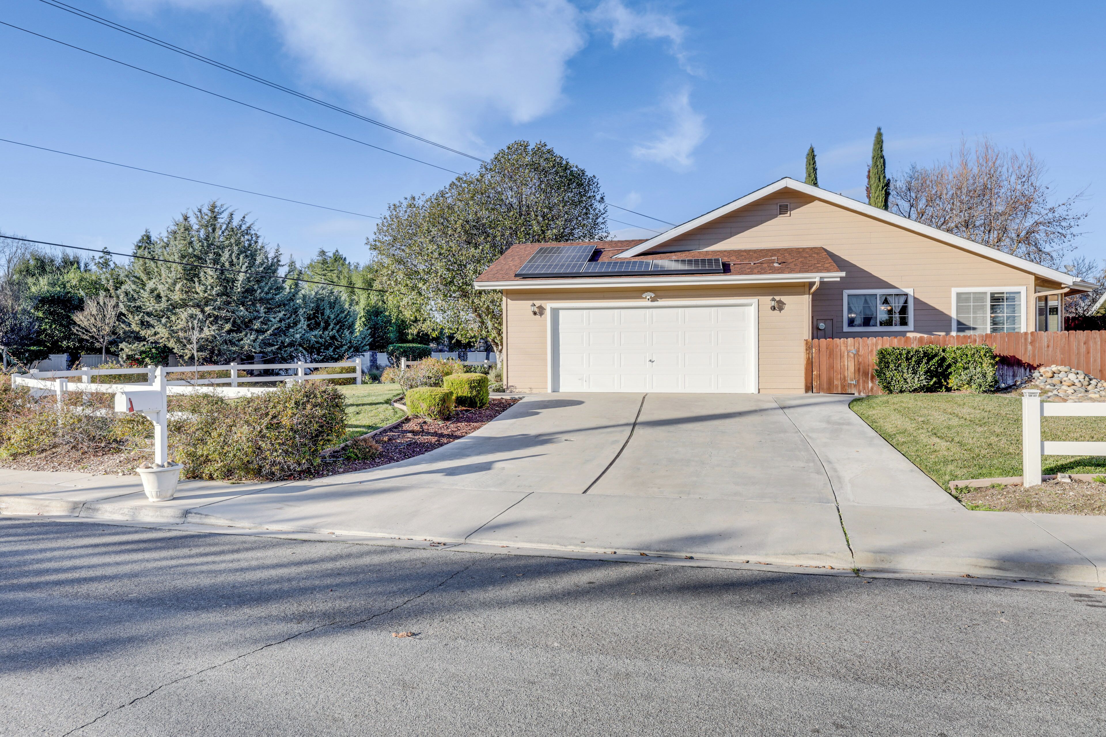 A single-story house with a garage, a driveway, and a fenced yard.