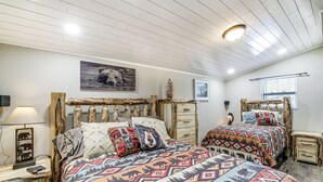 A bedroom with two wooden beds, a nightstand with a lamp, and a window with blinds. - Cozy Cottage w/ Pool Btwn Knoxville & Pigeon Forge (Kodak)