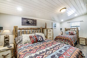 Cozy bedroom with two beds, a nightstand, and a framed picture, set against a rustic backdrop.