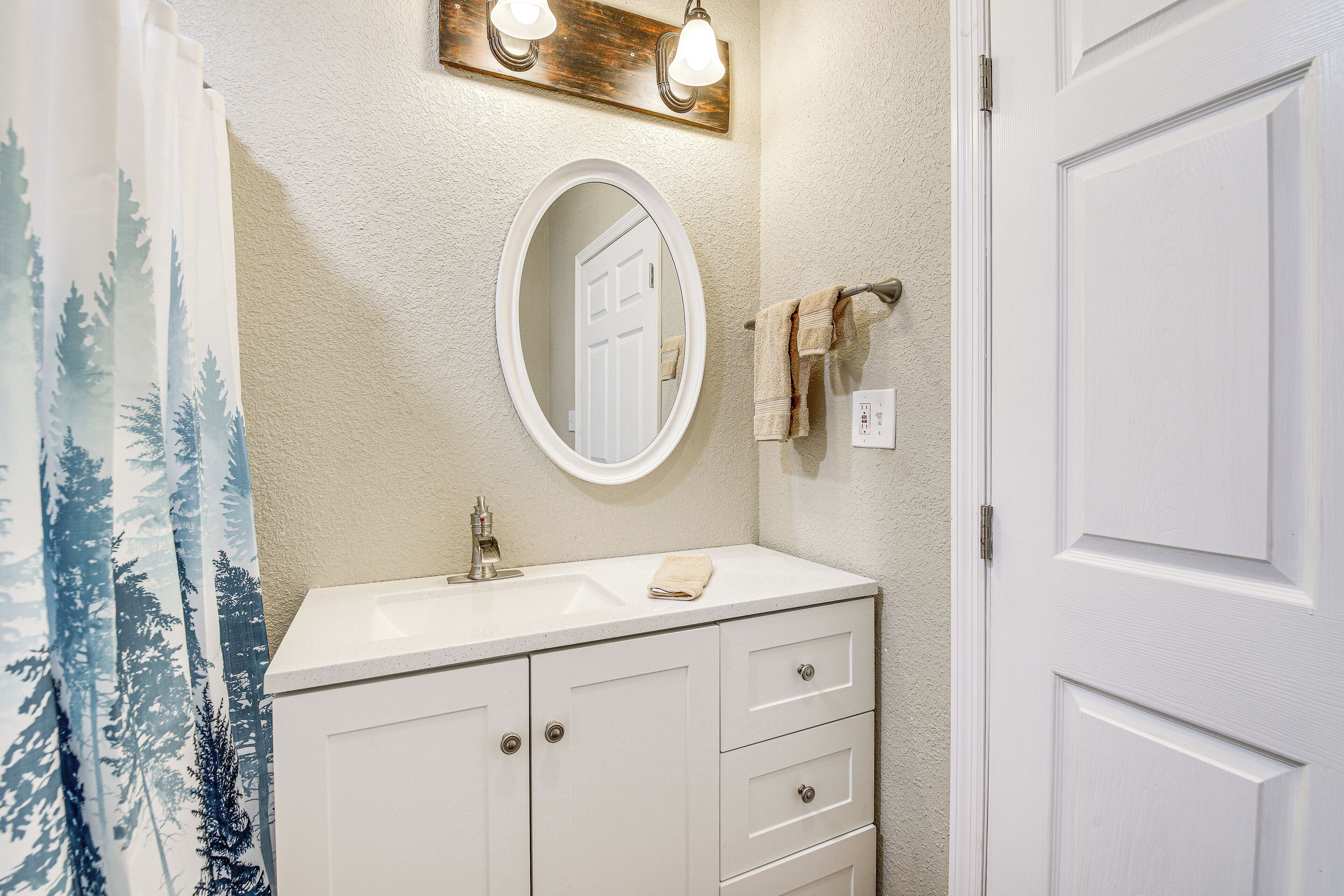 A bathroom with a white vanity, a mirror, and a towel rack.