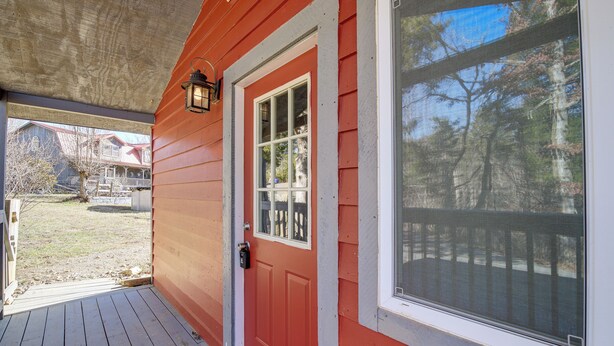 A red wooden house with a white door, a porch, and a large window. - Cozy Cottage w/ Pool Btwn Knoxville & Pigeon Forge (Kodak)