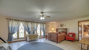 A spacious living room with a large rug, a dining table, a red armchair, a sofa, and a ceiling fan. - Quaint Youngstown Home ~ 2 Mi to Boardman Park! (Poland)