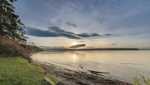 A calm lake with a grassy shore and trees. - Port Townsend Escape w/ Deck, Bay & Mountain Views (Port Townsend)