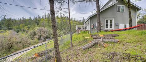 A house with a fenced yard, a hammock, and logs.