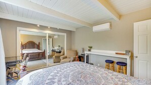 Une chambre à coucher avec un grand lit, un bureau avec deux tabourets, une chaise et une porte.