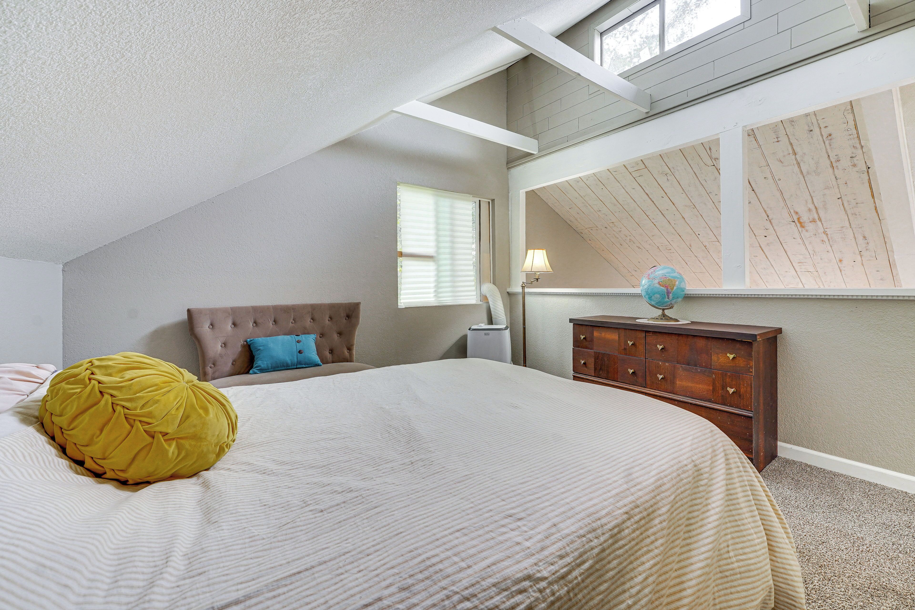 A bedroom with a bed, a dresser, a lamp, and a globe on the dresser.