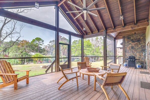 Enjoy al fresco dining with a barbecue grill and grill cart, surrounded by a landscaped garden with a body of water.