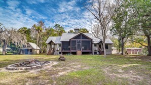 A large house with a spacious front yard, a fire pit, and a covered outdoor area. - Riverfront Fishers Paradise in Florida w/ Dock! (Inglis)