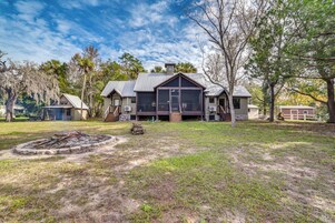 A large house with a spacious front yard, a fire pit, and a covered outdoor area.