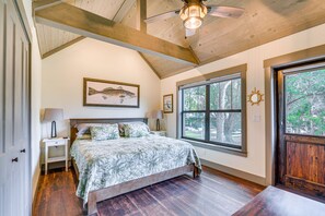 Cozy retreat with a large bed, sloped ceiling, and a window offering a view of the surrounding trees.