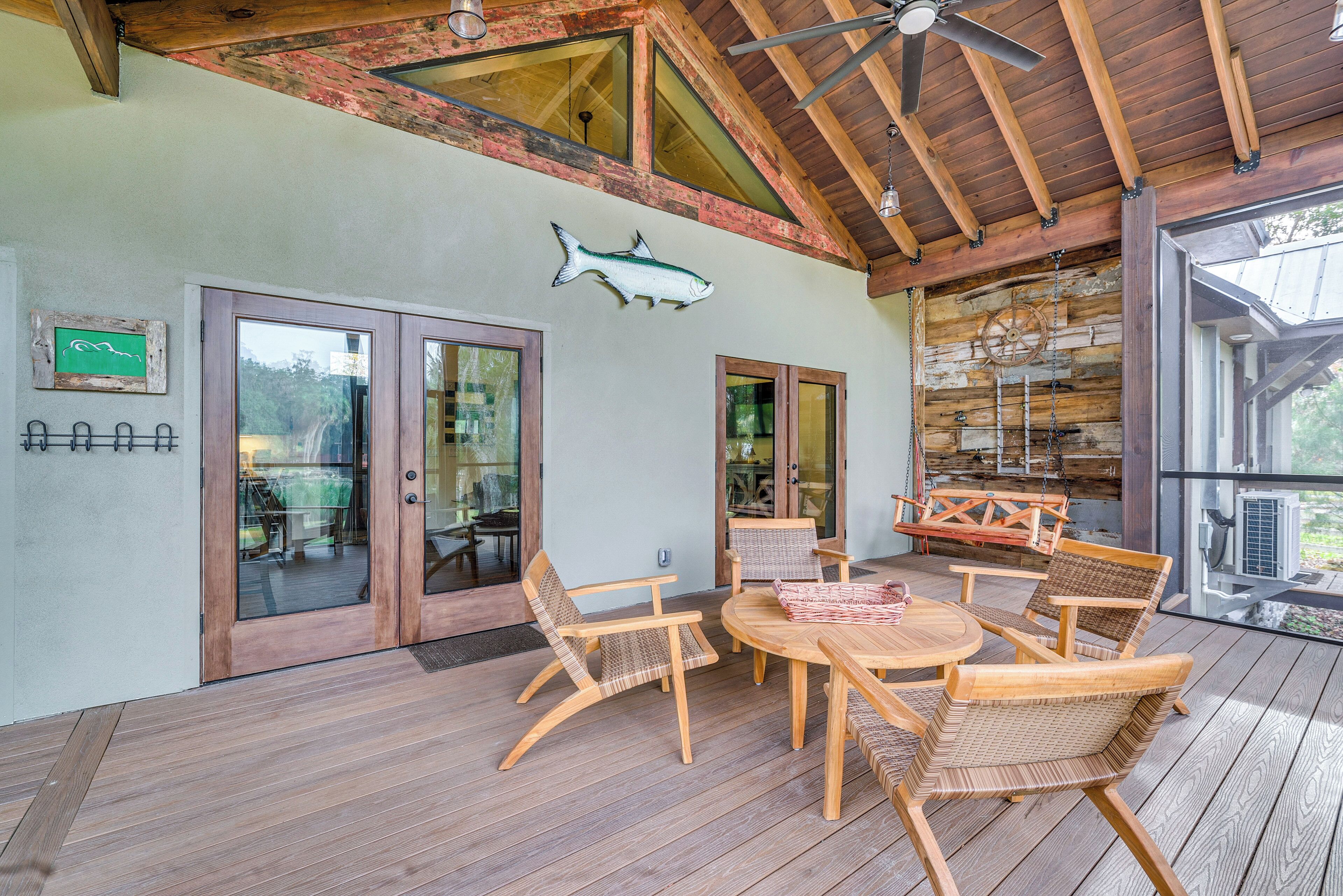 A wooden deck with wicker furniture and a ceiling fan.