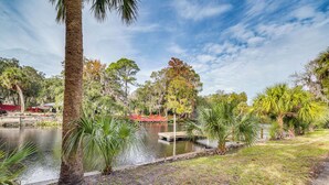 A serene park with a pond, palm trees, and a wooden dock. - Riverfront Fishers Paradise in Florida w/ Dock! (Inglis)