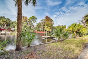 A serene park with a pond, palm trees, and a wooden dock.