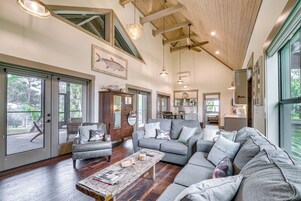 A spacious living room with a gray sectional sofa, a wooden coffee table, and a dining area with a table and chairs.