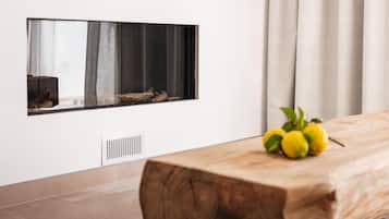A modern room with a wooden table, a mounted fireplace, and a window with curtains.