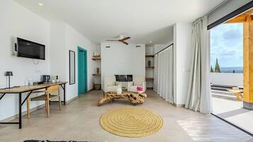 Una sala de estar moderna con televisor, una mesa de centro de madera, un tapete redondo y vistas al exterior.