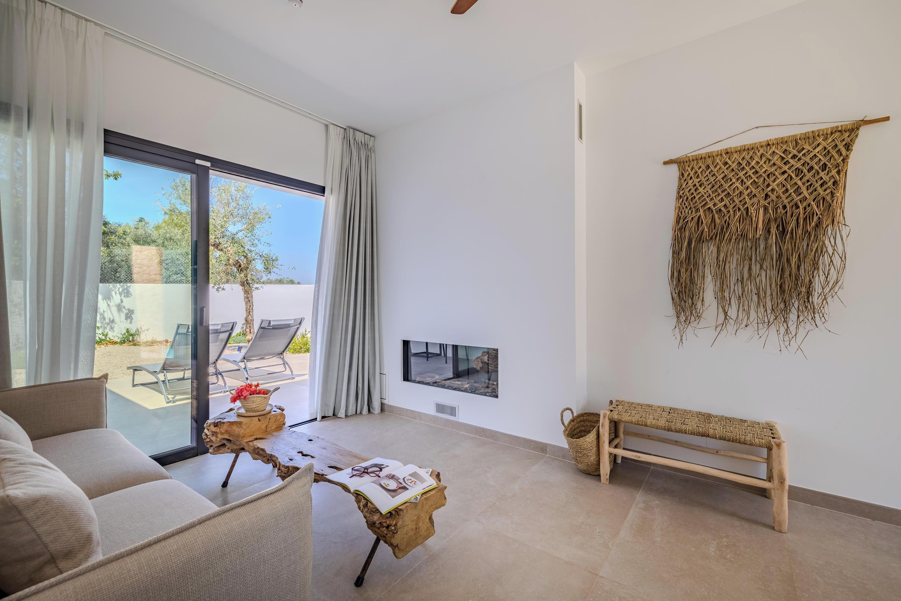 A modern living room with a sofa, a coffee table, a bench, and a TV mounted on the wall.