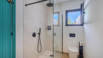A modern bathroom with a glass-enclosed shower, a toilet, and a window.