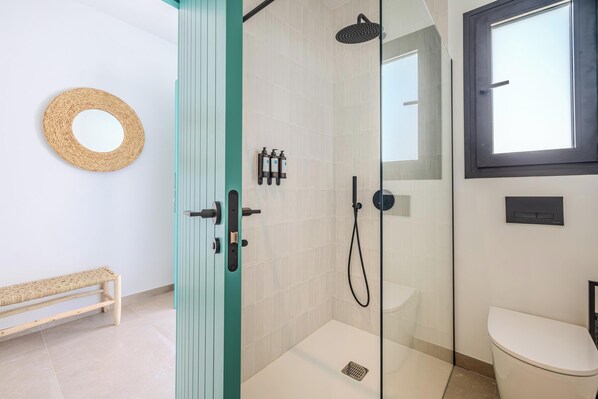 A modern bathroom with a glass shower enclosure, a toilet, and a bench. - Hotel Boutique Mi Almazara (Javea)