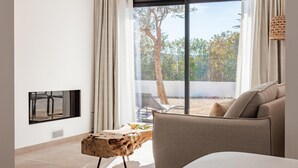 Un dormitorio moderno con un gran ventanal, un sofá, una mesita de centro de madera y un televisor montado en la pared.