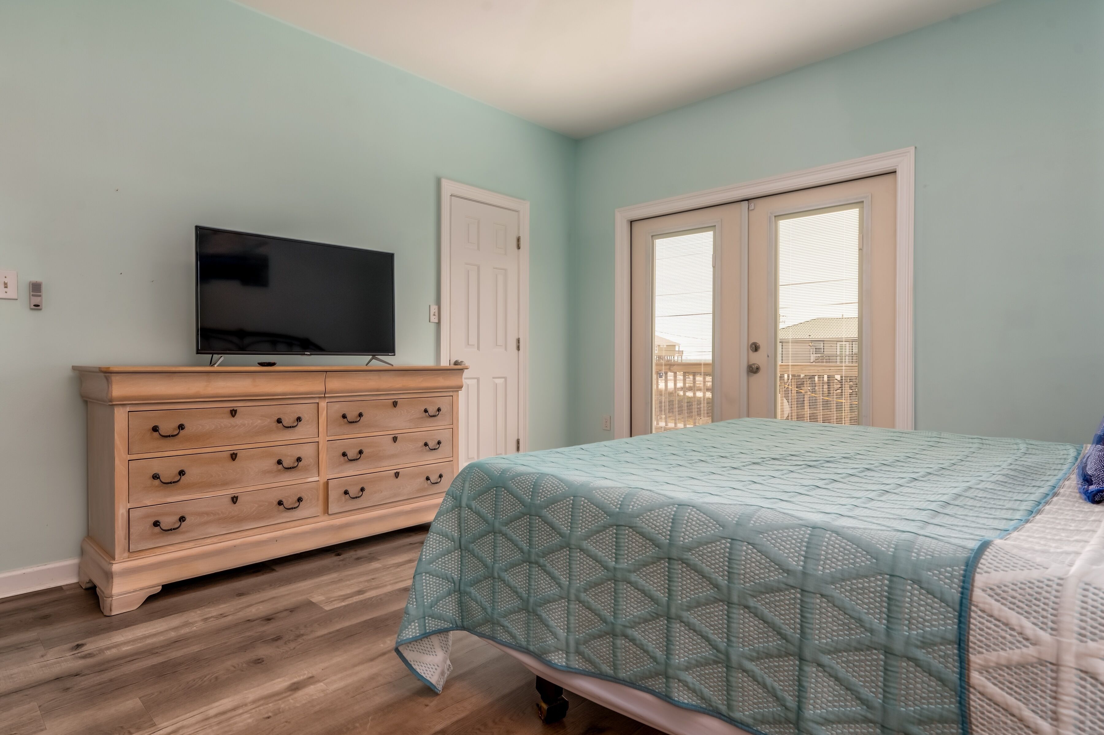 A bedroom with a bed, dresser, television, and a window.