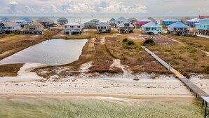 Una zona costera con casas sobre pilotes, un cuerpo de agua cristalina y una playa de arena.