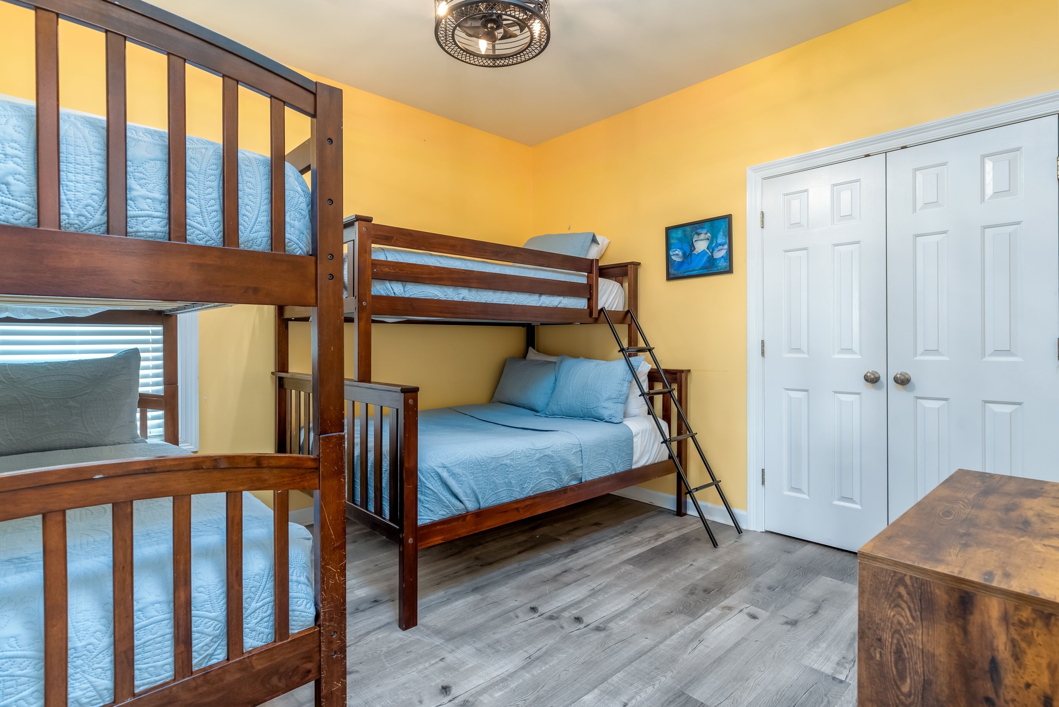 Een slaapkamer met een stapelbed, een witte deur en een schilderij aan de muur.