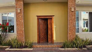 A two-story building with a central entrance, a balcony on the upper floor, and a paved ground area. - Beautiful 4-bed Villa in Dar es Salaam, Tanzania (Dar es Salaam)