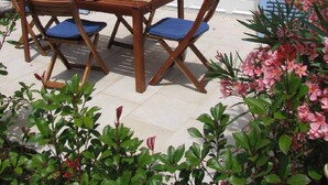 An outdoor dining area with a stone wall, blue shutters, and a table set for four. - Bastide du Soleil - 2-room apartment of 38m2 with terrace (CANNES)