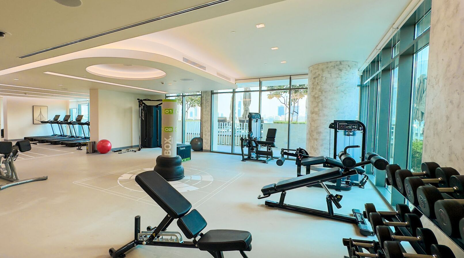 A modern gym with treadmills, weight machines, and exercise balls.