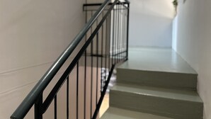 Un escalier avec une rampe en métal noir et des marches de couleur beige.