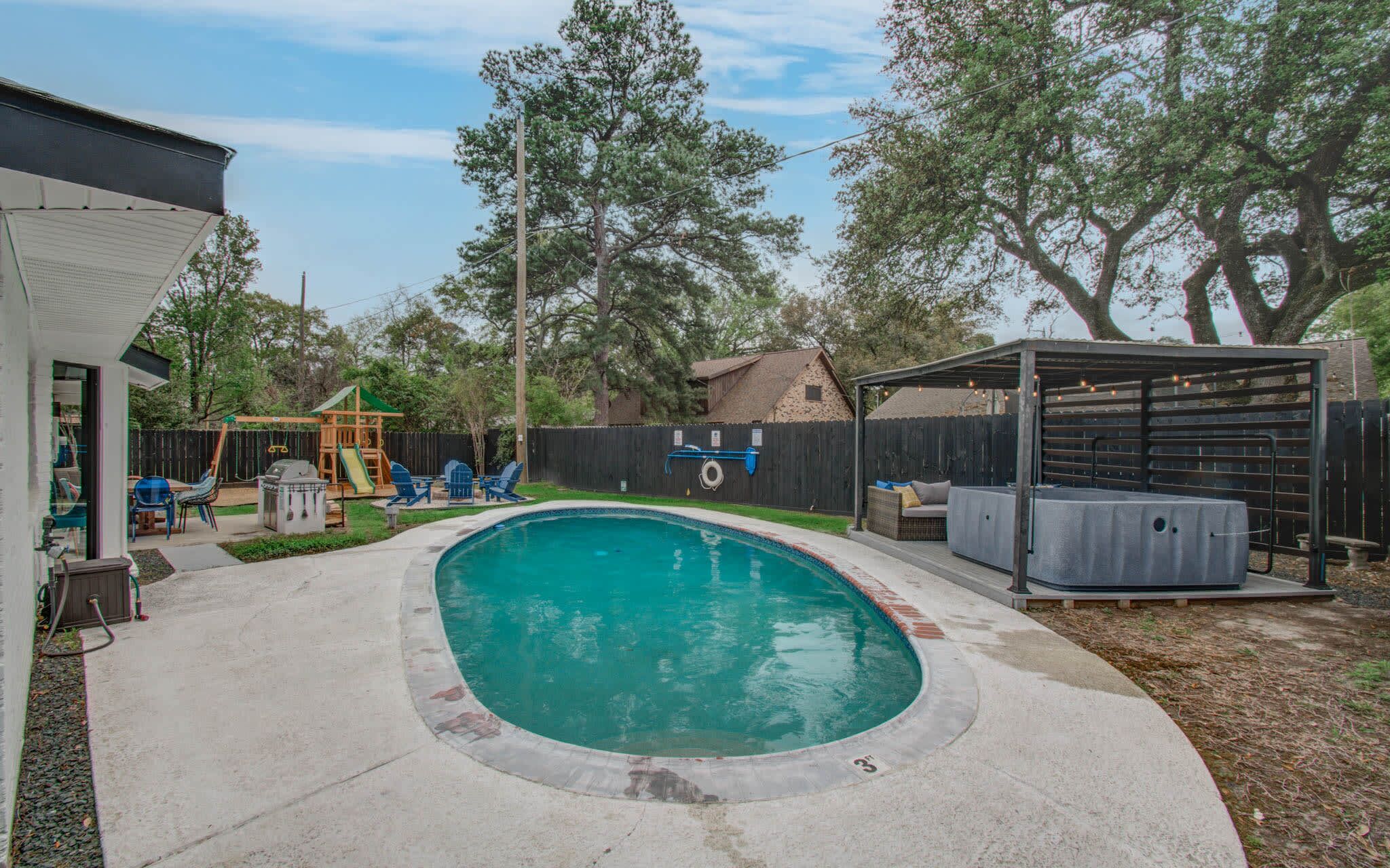 This tropical backyard oasis features an outdoor swimming pool, a covered cabana, a furnished patio, a hot tub, a fire pit, and a kid’s playground – what more could anyone ask for?!