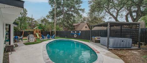 This tropical backyard oasis features an outdoor swimming pool, a covered cabana, a furnished patio, a hot tub, a fire pit, and a kid’s playground – what more could anyone ask for?!