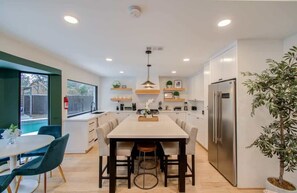 Una cocina moderna con una isla central, armarios blancos y un refrigerador empotrado.