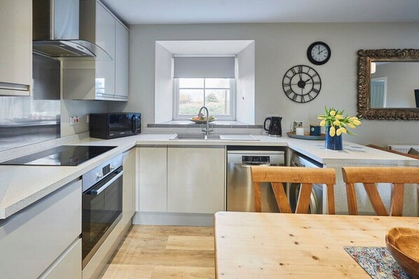 Enjoy cooking in this well-equipped kitchen with a central island, sink, and microwave, plus a dining area with a table and chairs.