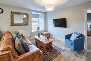 Relax in this stylish living room with a leather sofa, armchair, and flat-screen TV.