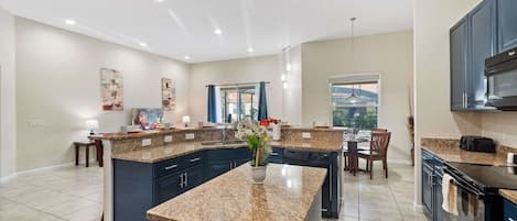 A modern kitchen with granite countertops, dark cabinetry, and a central island.