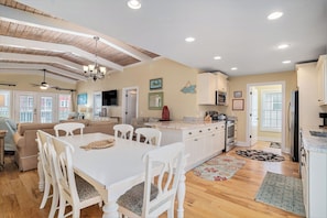 A spacious kitchen with a dining area, wooden ceiling, and modern appliances.