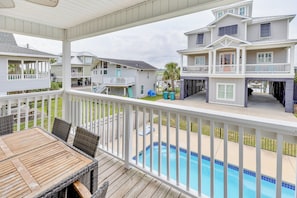 A covered outdoor area with a pool, wooden deck, and a view of neighboring houses.